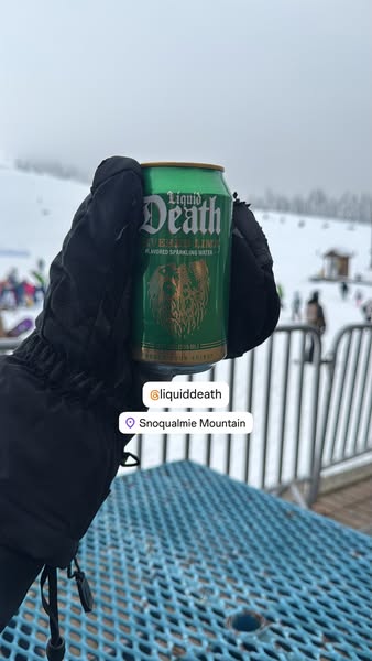Liquid Death creator UGC ad: a hand holds a can of Liquid Death Severed Lime at a ski resort, tagged @liquiddeath at Snoqualmie Mountain.